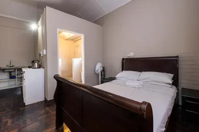 a bedroom with a large bed and a kitchen at De Oude Hof Lodge in Delmas