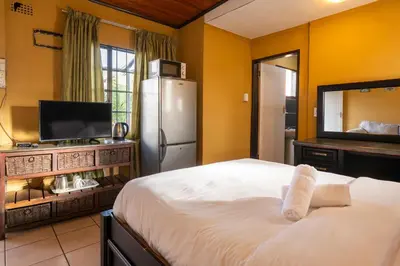 a bedroom with a white bed and a television at De Oude Hof Lodge in Delmas