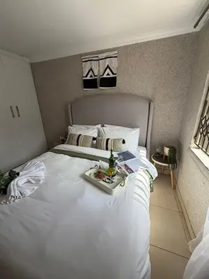 a large white bed with a tray of food on it at Shayas Haven in Thohoyandou