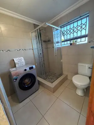 a bathroom with a shower and a washing machine at Shayas Haven in Thohoyandou