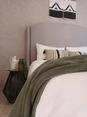a bedroom with a bed with a green blanket on it at Shayas Haven in Thohoyandou