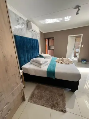 a bedroom with a large bed with a blue headboard at Pool house 39 hoog in Polokwane