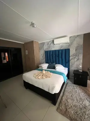 a bedroom with a large bed with a blue headboard at Pool house 39 hoog in Polokwane