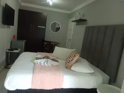 a bedroom with a white bed with two bags on it at Pool house 39 hoog in Polokwane