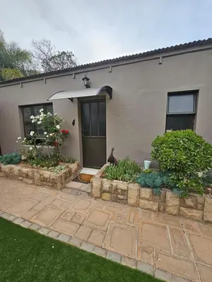 a cat sitting in front of a house at Pool house 39 hoog in Polokwane