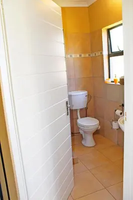 a bathroom with a toilet and a window at Pool house 39 hoog in Polokwane