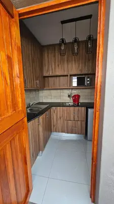 a kitchen with wooden cabinets and a white tile floor at Pool house 39 hoog in Polokwane
