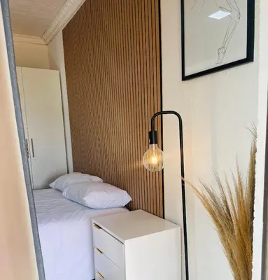 a small bedroom with a bed and a lamp at Makgobelo Lodge -The White House - Solar powered in Ga-Mokalapa