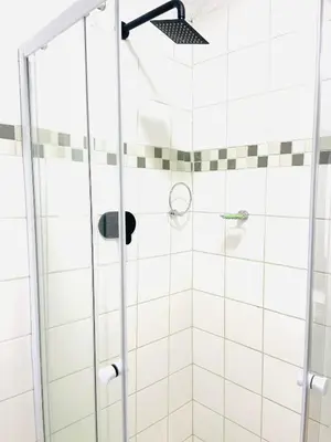 a shower in a bathroom with white tiles at Makgobelo Lodge -The White House - Solar powered in Ga-Mokalapa