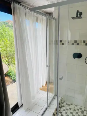 a bathroom with a shower with a glass door at Makgobelo Lodge -The White House - Solar powered in Ga-Mokalapa