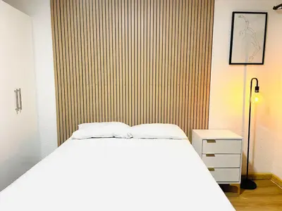 a bedroom with a white bed and a wooden wall at Makgobelo Lodge -The White House - Solar powered in Ga-Mokalapa