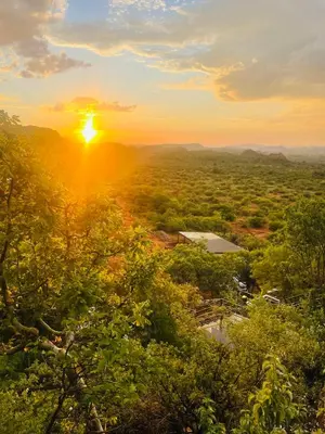 a sunset from the top of a hill with trees at Makgobelo Lodge -The White House - Solar powered in Ga-Mokalapa