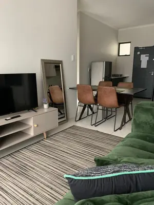 a living room with a tv and a table and chairs at Umunlád Suites in Midrand