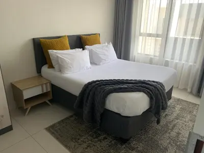 a bedroom with a large bed with a blanket on it at Umunlád Suites in Midrand