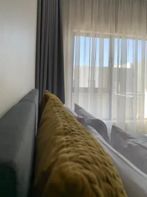 a bed with a yellow blanket in front of a window at Umunlád Suites in Midrand