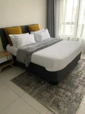 a bed with white sheets and pillows in a bedroom at Umunlád Suites in Midrand
