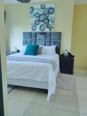 a bedroom with a large bed with blue and white pillows at Choosers Express Boutique Hotel Room 5 in Centurion
