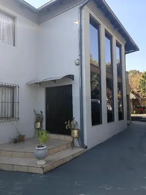 a white house with a porch and a black door at Choosers Express Boutique Hotel Room 5 in Centurion