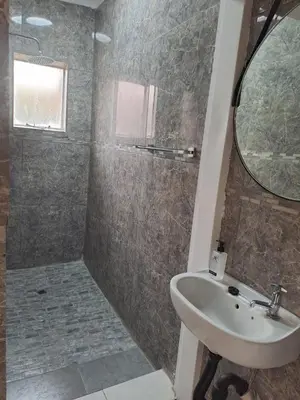 a bathroom with a sink and a shower with a mirror at Hazel Haven 1 Guest House in Pretoria