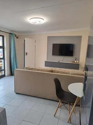 a room with a bed and a chair and a tv at Hazel Haven 1 Guest House in Pretoria