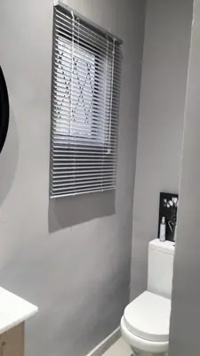 a bathroom with a toilet and a window with blinds at J & M Elegant Escape in Centurion