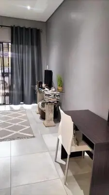 a living room with a table and a desk with a computer at J & M Elegant Escape in Centurion