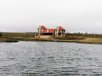 a house with a red roof next to a body of water at Troutmere in Belfast