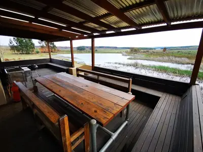 a wooden table on a deck with two benches at Troutmere in Belfast