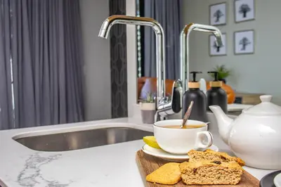 a kitchen counter with a cup of tea and bread at Exclusive Apartment, Ellipse in Midrand