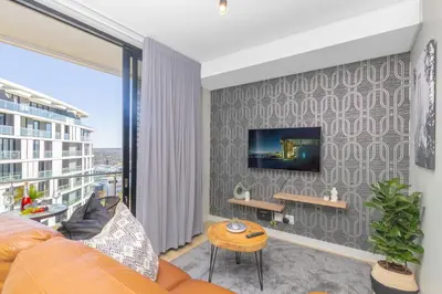 a living room with a couch and a tv on a wall at Exclusive Apartment, Ellipse in Midrand