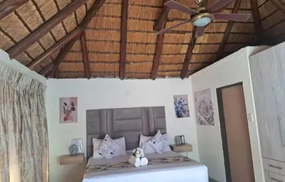a bedroom with a bed with a ceiling fan at Glamour C-rane lodge in Phalaborwa