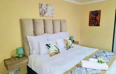 a bedroom with a large bed with white sheets and pillows at Glamour C-rane lodge in Phalaborwa