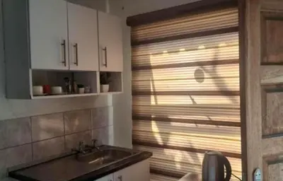 a kitchen with a sink and a window with blinds at Glamour C-rane lodge in Phalaborwa