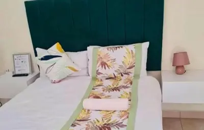 a bedroom with a bed with a green headboard and pillows at Glamour C-rane lodge in Phalaborwa