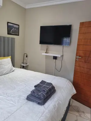 a bedroom with a bed with a flat screen tv on the wall at Leetong Holiday Home in Hazyview