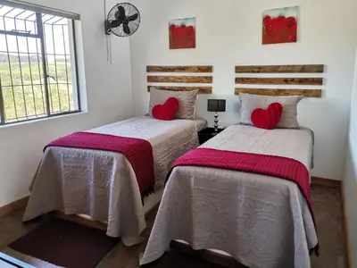 two beds in a room with red pillows at Levubu Junction Lodge in Louis Trichardt