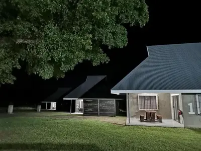 a house with a black roof and a yard at Levubu Junction Lodge in Louis Trichardt