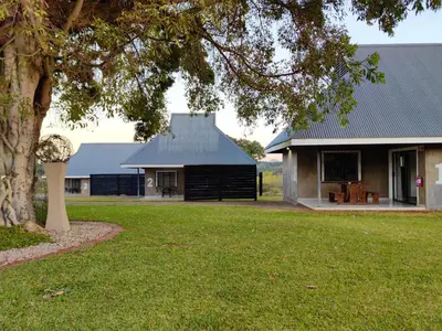 a house with a black roof and a tree at Levubu Junction Lodge in Louis Trichardt