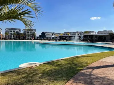 a large swimming pool with a palm tree and a fountain at The Blyde Crystal Lagoon Penthouse in Avondzon