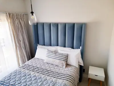 a bed with a blue headboard in a bedroom at The Blyde Crystal Lagoon Penthouse in Avondzon