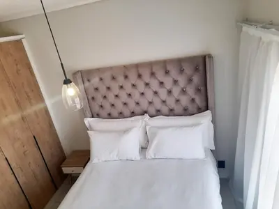 a bed with a headboard and white pillows at The Blyde Crystal Lagoon Penthouse in Avondzon