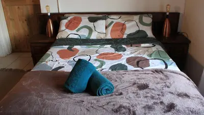 a bed with a blue towel on it at The Seed Pod Guesthouse in Modimolle