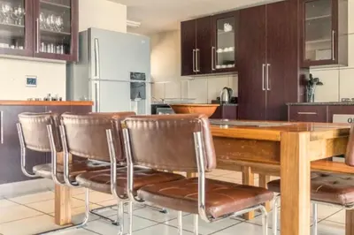 a kitchen with a wooden table and leather chairs at Zebula Bush Villa 82, Zebula Golf Estate and Spa in Mabula