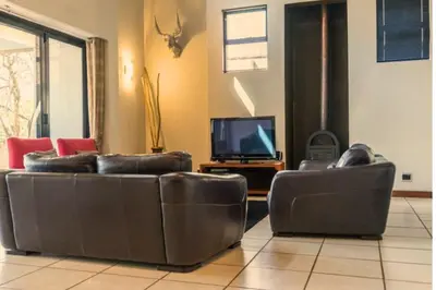 a living room with two leather couches and a television at Zebula Bush Villa 82, Zebula Golf Estate and Spa in Mabula