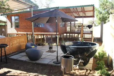 a bath tub and an umbrella in a yard at Romantic cabin in Big 5 Reserve in Dinokeng Game Reserve