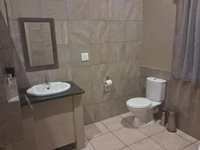 a bathroom with a toilet and a sink and a mirror at The Sanctuary- Self Catering Accommodation in Nelspruit