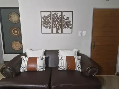 a brown leather couch with three pillows on it at Heavenly Hideaway Accommodation in Kampersrus AH