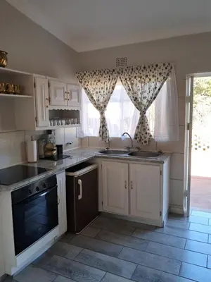 a kitchen with white cabinets and a large window at 15 Kameeldoring 2-bedroomed self-catering unit, Clubview in Centurion
