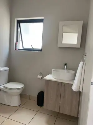 a white bathroom with a toilet and a sink at 1 Bedroom Sleek, Spotless, Work-from-home Sanctuary in Midrand