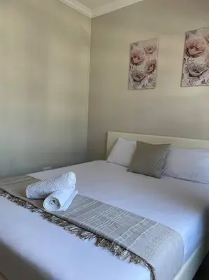 a white bed with two towels on top of it at 1 Bedroom Sleek, Spotless, Work-from-home Sanctuary in Midrand